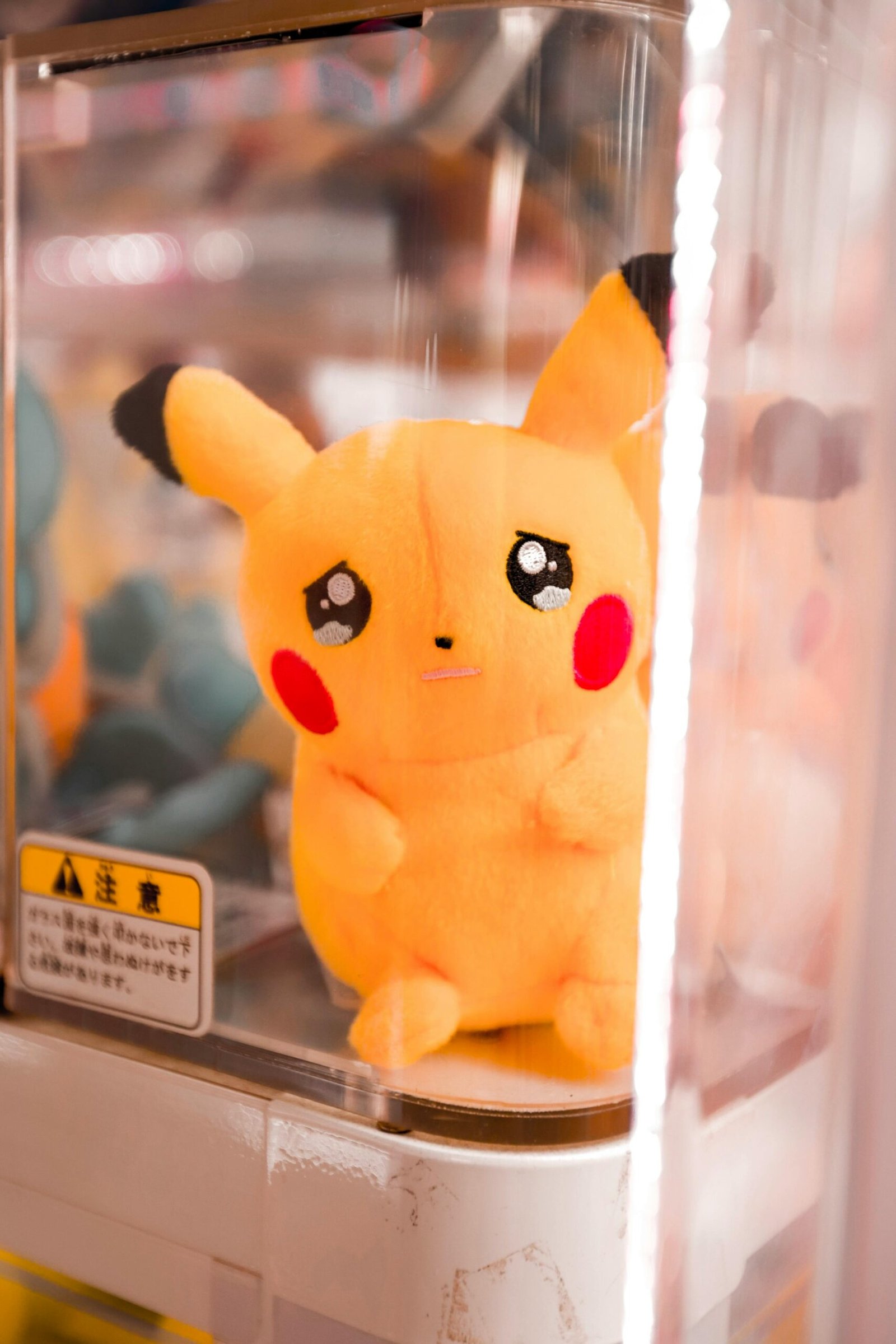 Cute Pikachu plush toy inside a claw machine in a Japanese arcade.
